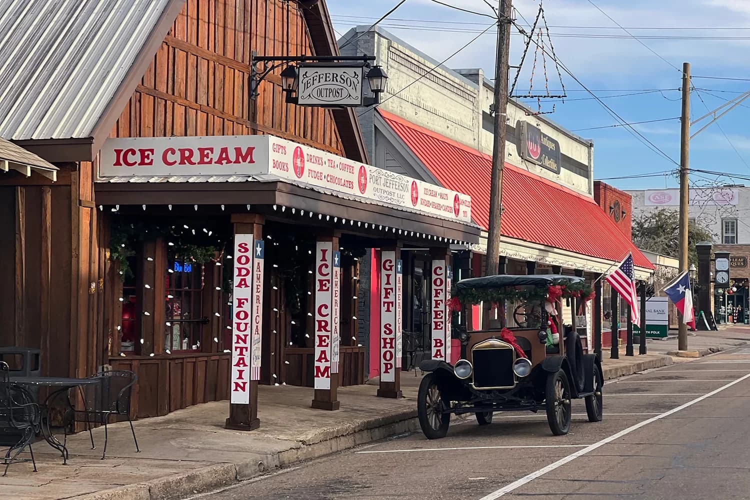 A vintage car is parked in front of a quaint ice cream shop along a charming street.